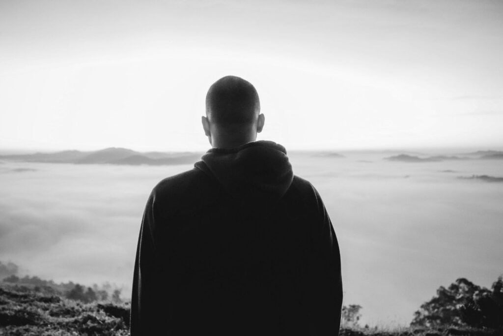 Homme seul de dos contemplant l’horizon dans le silence, symbole d’introspection et de force intérieure