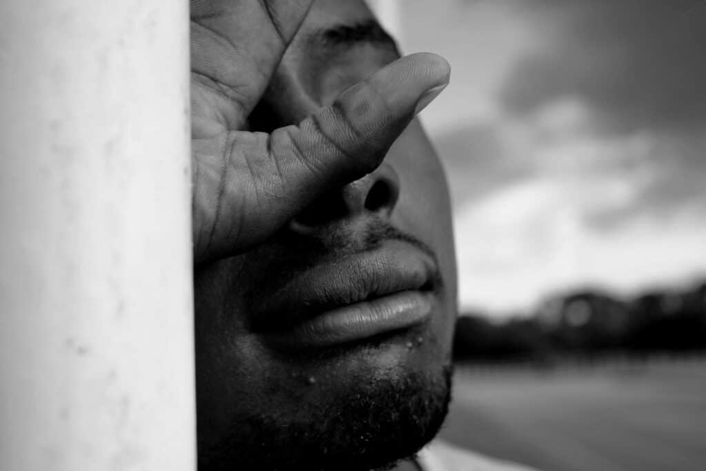 Homme timide partiellement caché, regard fuyant, illustrant la peur du jugement et le repli sur soi.