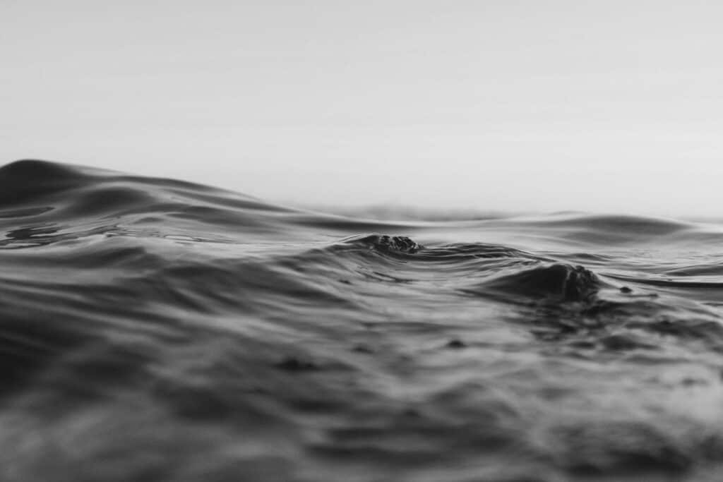 Surface de la mer calme en noir et blanc, avec de légères vagues évoquant le silence et la profondeur.