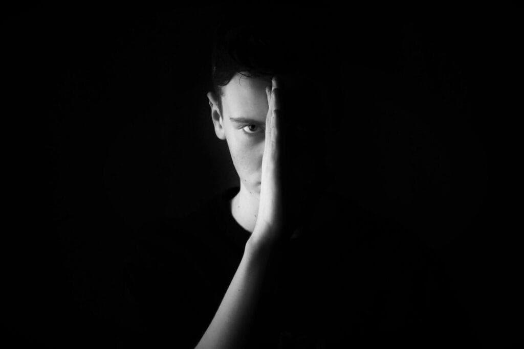 Homme dans l’ombre, regard intérieur et concentré, incarnant la maîtrise de soi et la force silencieuse.